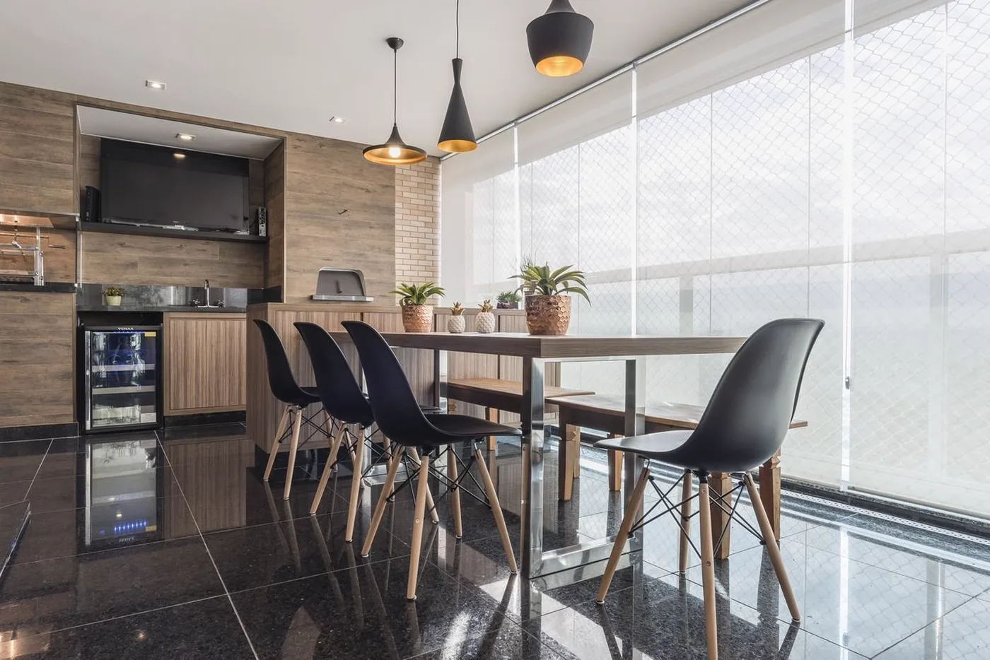 Varanda gourmet de apartamento com persiana de tela solar descida, mantendo a vista da cidade